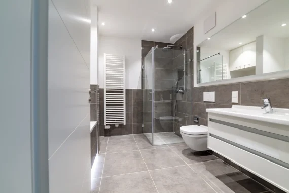 Grey tiled bathroom with walk-in glass shower and white floating vanity, bathroom remodeling in Libertyville